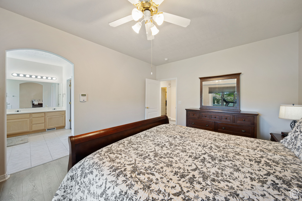 Bedroom with light wood-type flooring, ensuite bath, and a ceiling fan