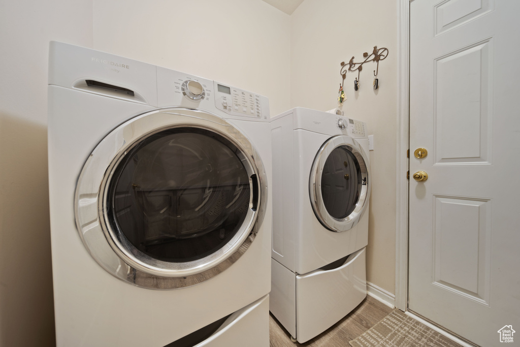 Washroom featuring independent washer and dryer, light wood-type flooring, and baseboards