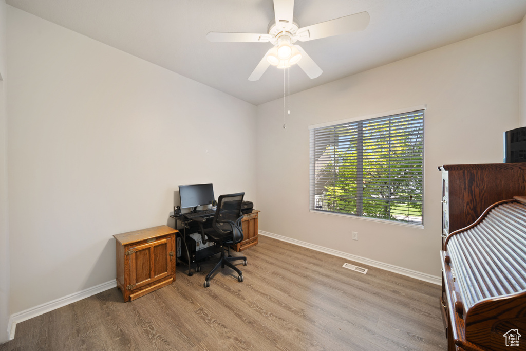 Office area with light wood-style flooring, baseboards, and ceiling fan