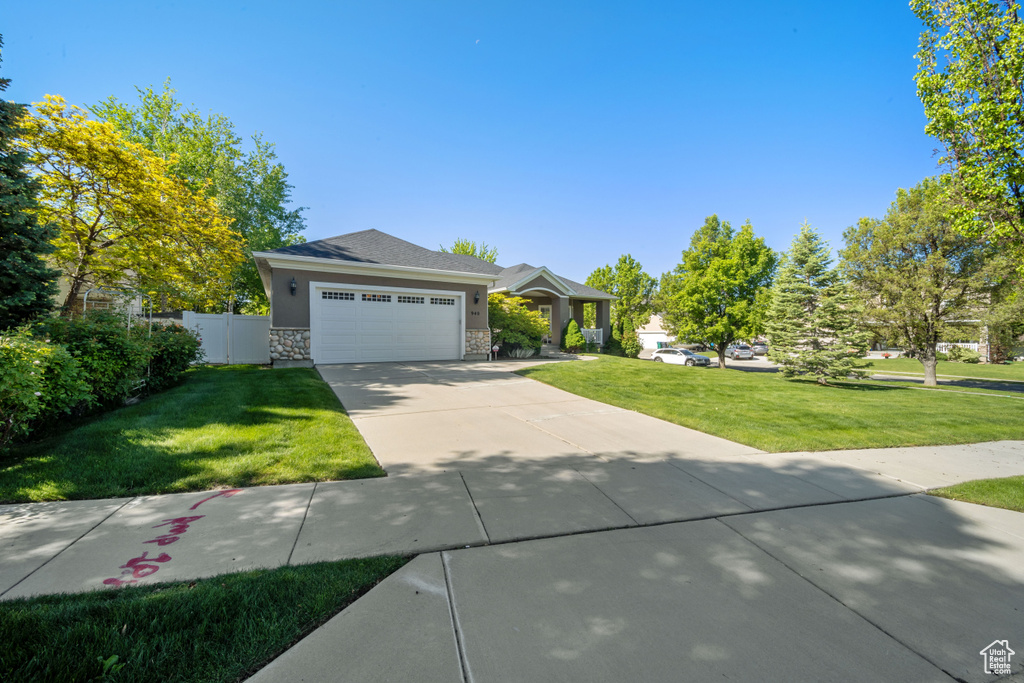 View of front of home featuring driveway, a garage, and stone siding