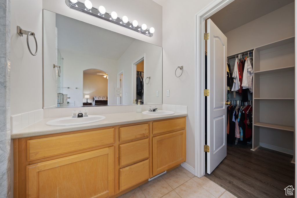 Full bath with double vanity, a walk in closet, and tile patterned floors