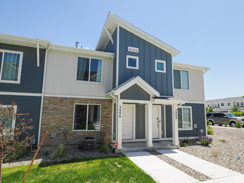 View of front of home featuring board and batten siding, stone siding, and cooling unit