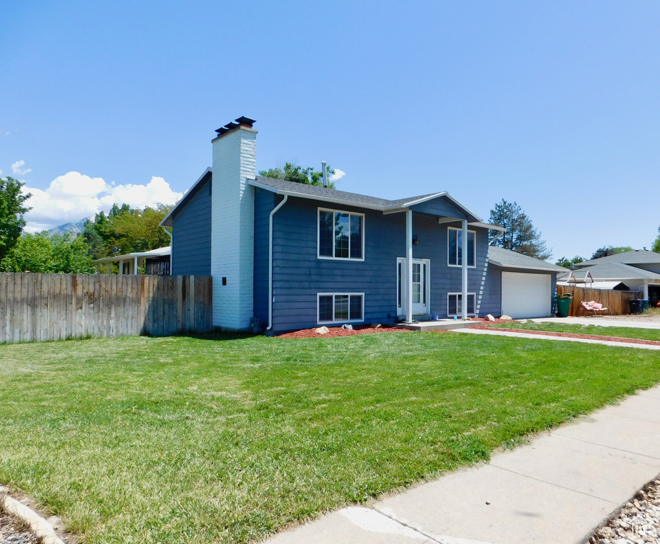 Raised ranch with a chimney, a garage, and concrete driveway