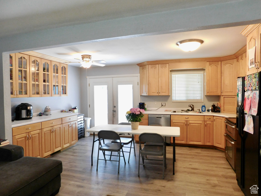Kitchen featuring light brown cabinetry, black refrigerator with ice dispenser, double oven range, and glass insert cabinets