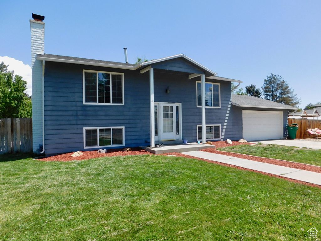 Split foyer home with a chimney, driveway, and an attached garage