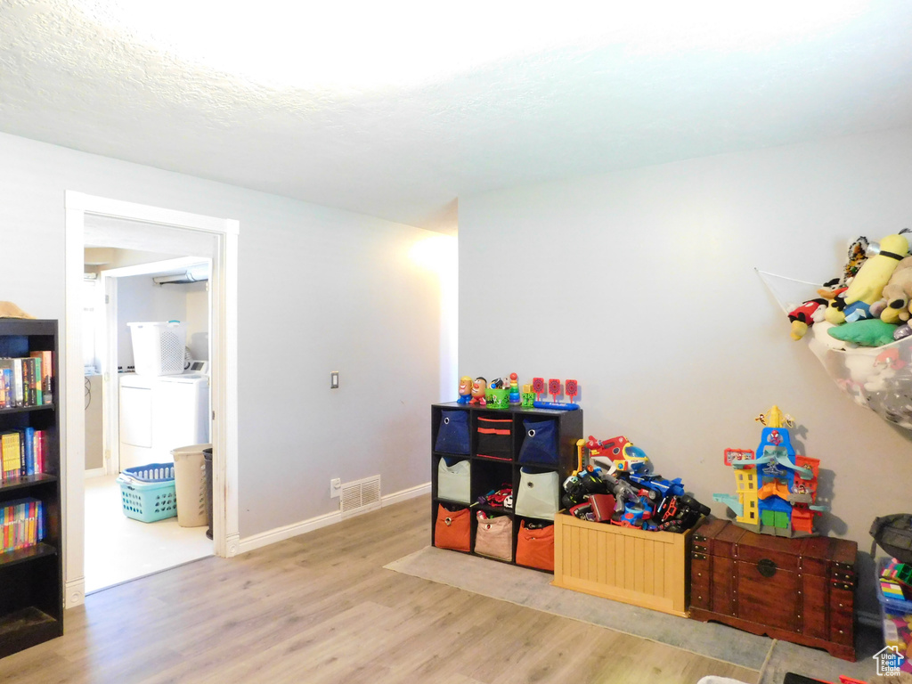 Recreation room with washer and clothes dryer, light wood-style floors, and baseboards