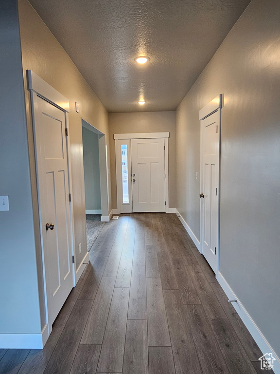 Foyer entrance with a textured ceiling, dark wood-style floors, and baseboards