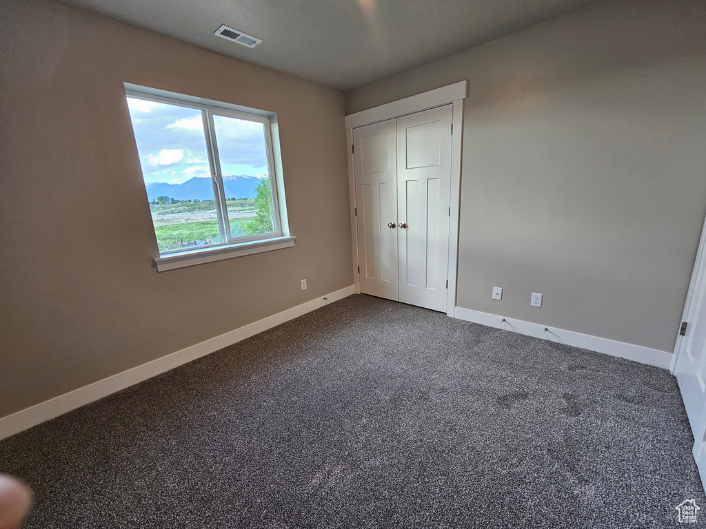 Unfurnished bedroom with baseboards and dark carpet