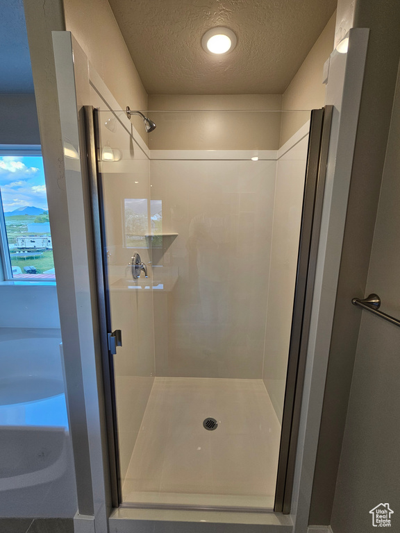 Full bathroom featuring a textured ceiling and a stall shower