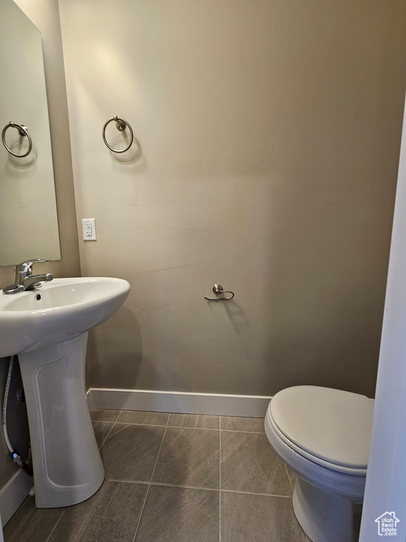 Bathroom with baseboards, toilet, a sink, and tile patterned flooring