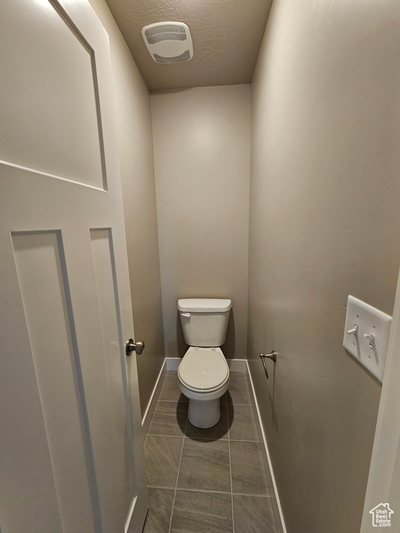 Bathroom featuring a textured ceiling, toilet, and baseboards