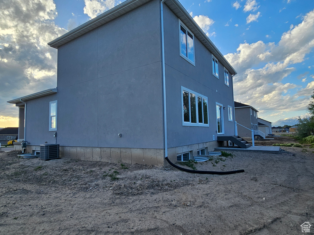 View of side of property with entry steps, stucco siding, and central air condition unit