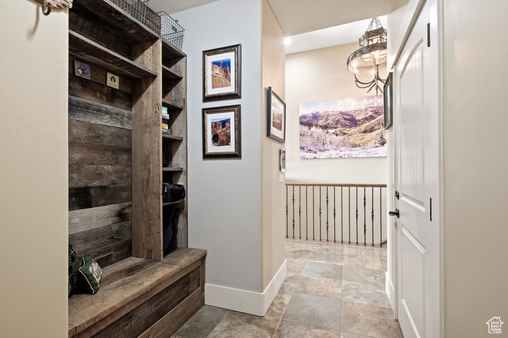 Mudroom with baseboards, stone finish floors, and a chandelier
