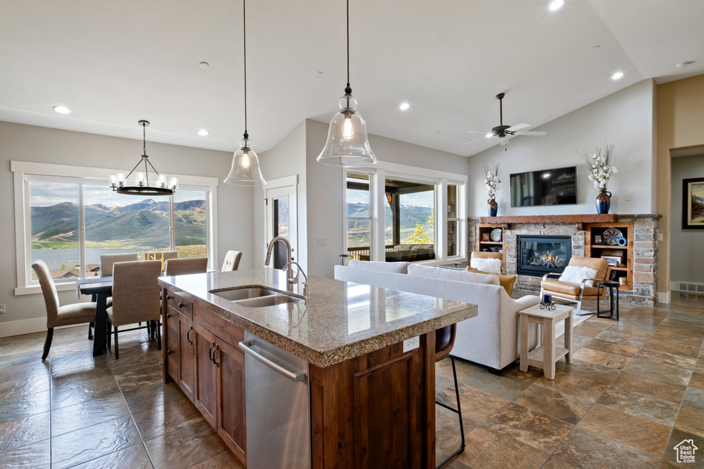 Kitchen with a fireplace, recessed lighting, stone tile flooring, a center island with sink, and a sink