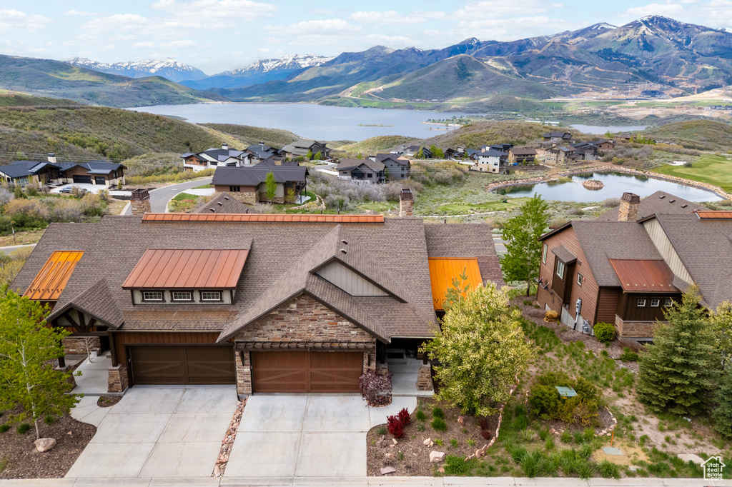 View of front of property with a chimney, stone siding, concrete driveway, and a water and mountain view