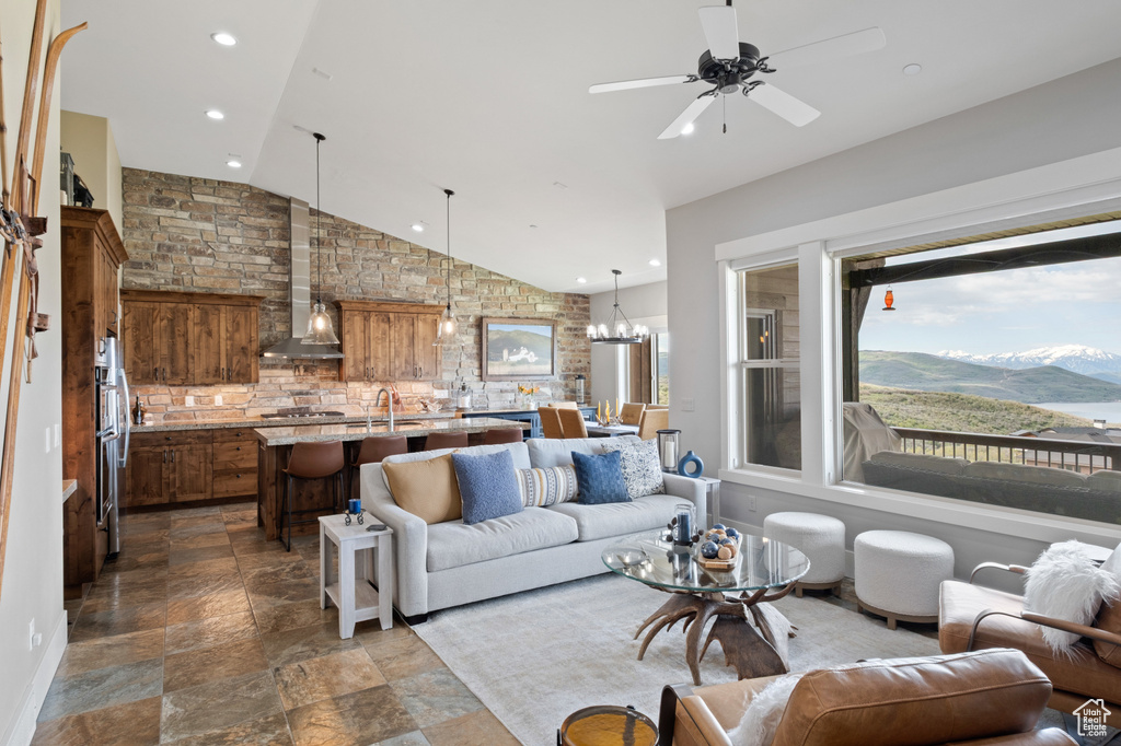 Living room featuring dark stone finish flooring, vaulted ceiling, a ceiling fan, a mountain view, and recessed lighting