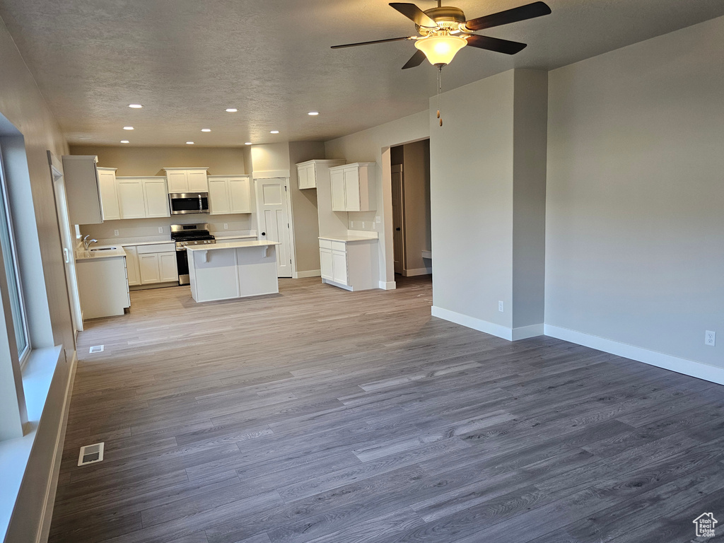 Kitchen with appliances with stainless steel finishes, open floor plan, recessed lighting, a ceiling fan, and wood finished floors