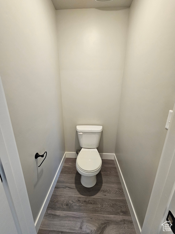 Bathroom featuring wood finished floors, toilet, and baseboards
