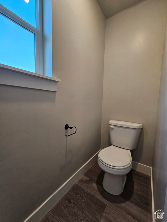 Bathroom with wood finished floors, toilet, and baseboards