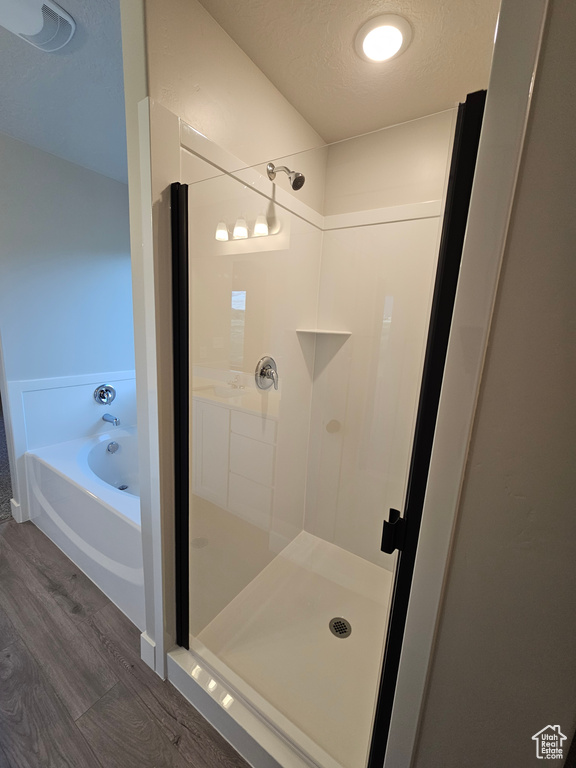 Full bath featuring wood finished floors, a shower stall, and a garden tub