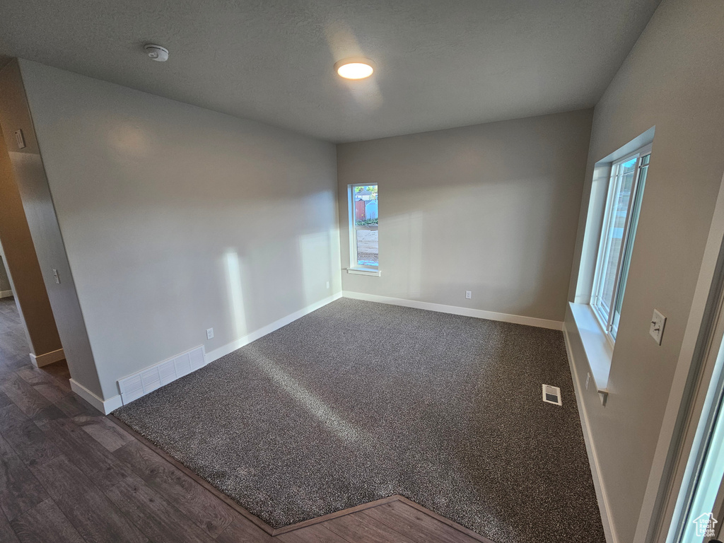 Spare room with a smoke detector, baseboards, and dark wood-style flooring