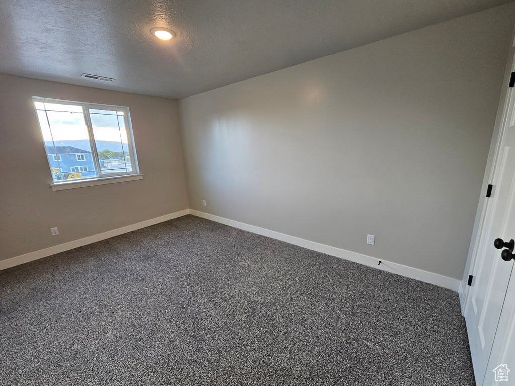 Unfurnished room with dark colored carpet, baseboards, and a textured ceiling