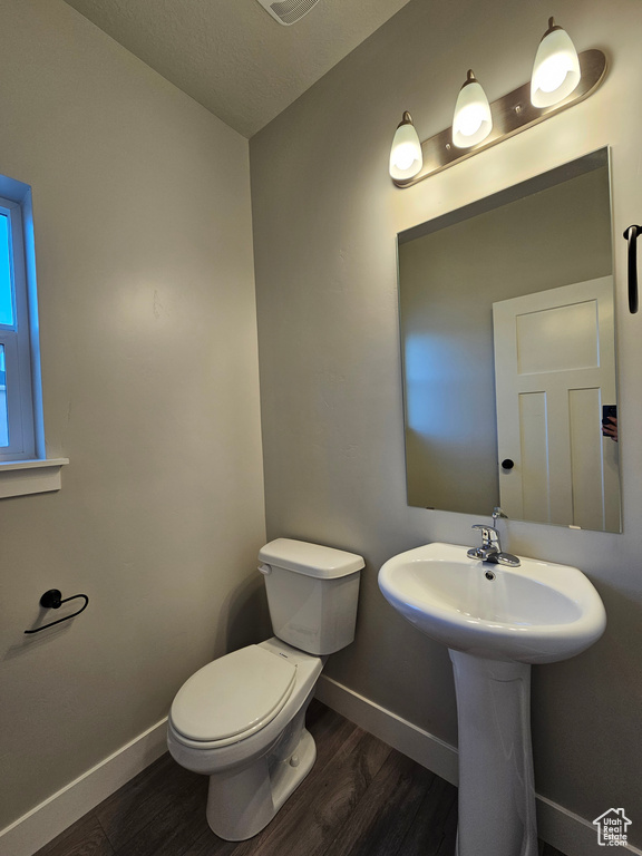 Half bathroom with wood finished floors, baseboards, and toilet