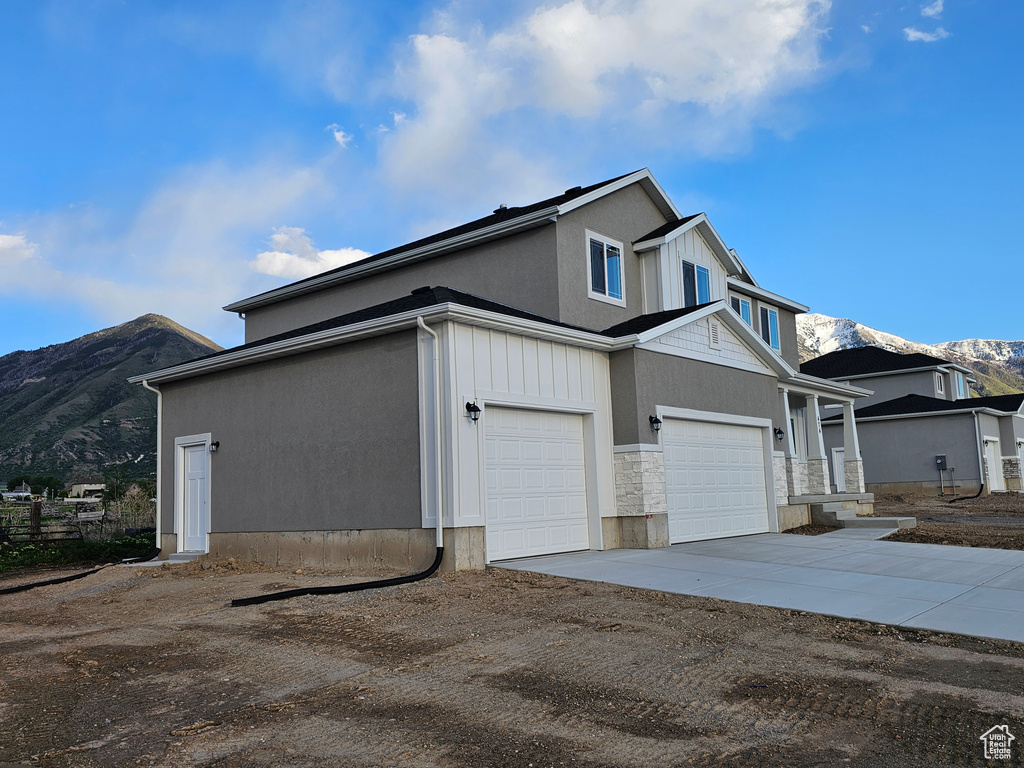 View of home's exterior with a mountain view, driveway, and stone siding