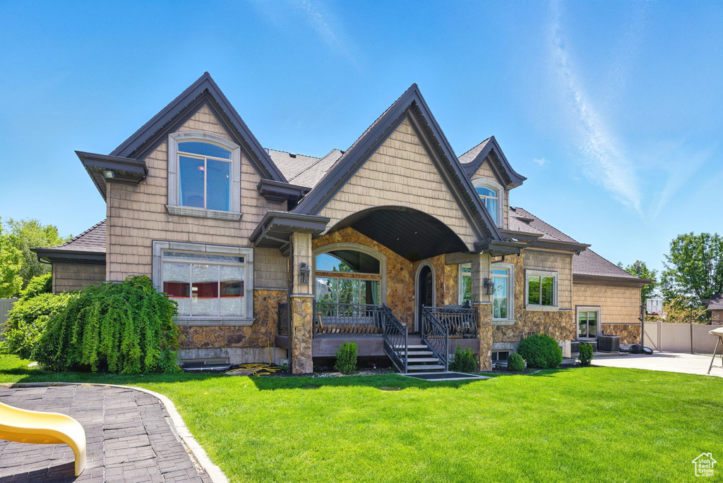 View of front of property featuring covered porch, stone siding, and a patio area