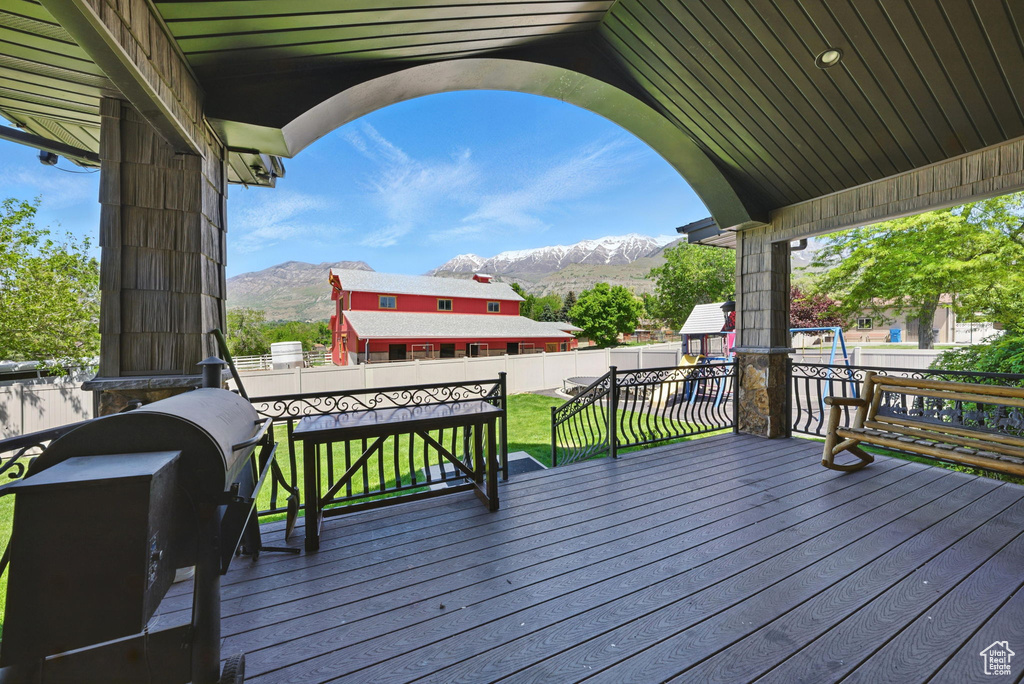 Wooden deck featuring a mountain view and a playground
