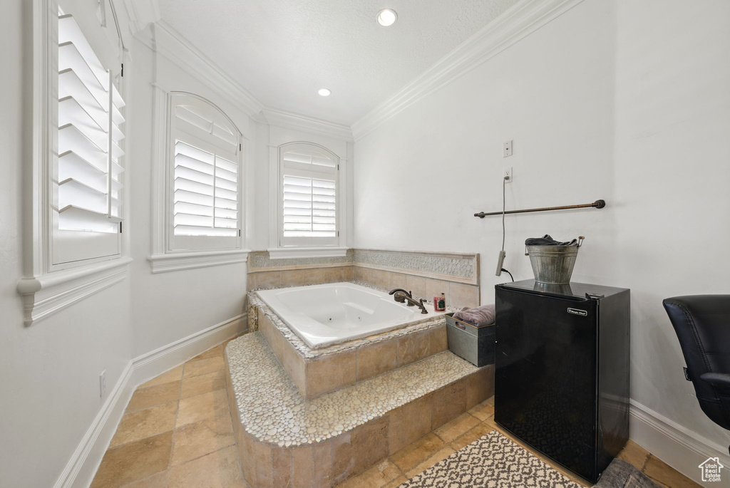 Bathroom featuring ornamental molding, a whirlpool tub, baseboards, stone tile floors, and recessed lighting