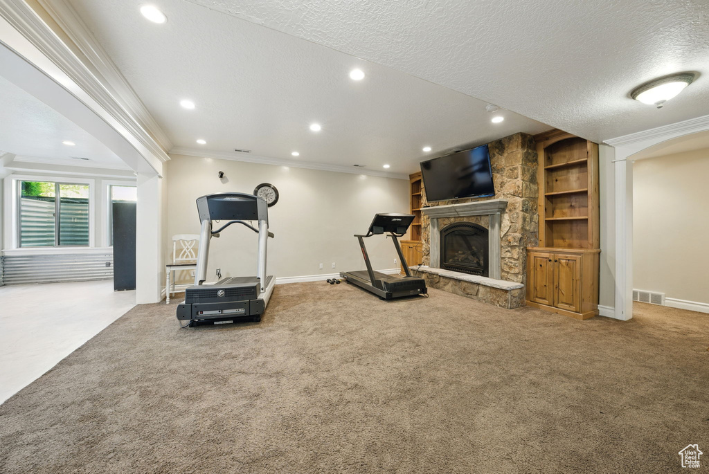 Exercise area featuring carpet flooring, recessed lighting, a fireplace, baseboards, and ornamental molding