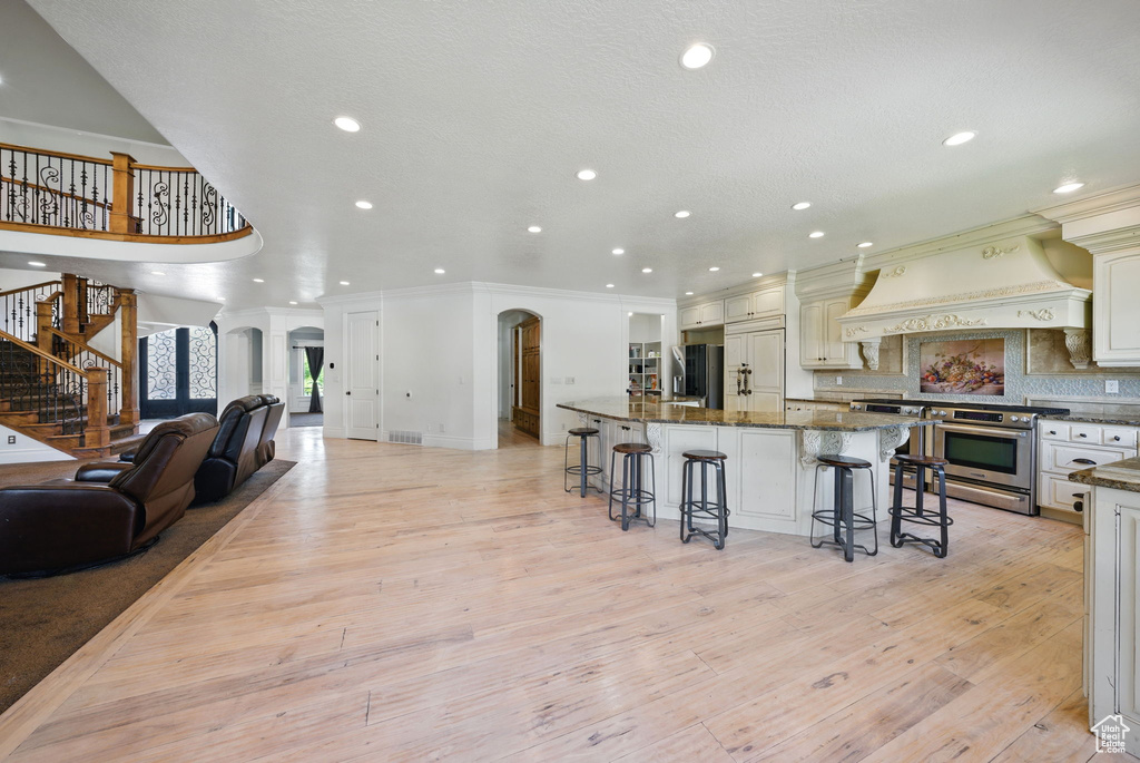 Kitchen featuring stainless steel appliances, a breakfast bar area, recessed lighting, crown molding, and a spacious island