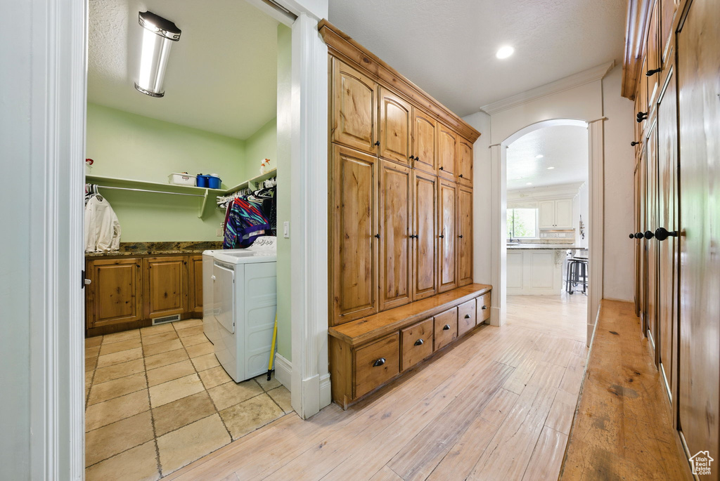Laundry room featuring washer / clothes dryer, cabinet space, arched walkways, light wood-style floors, and recessed lighting