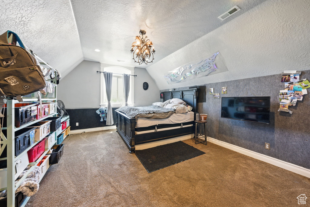 Carpeted bedroom with a textured ceiling, vaulted ceiling, and baseboards