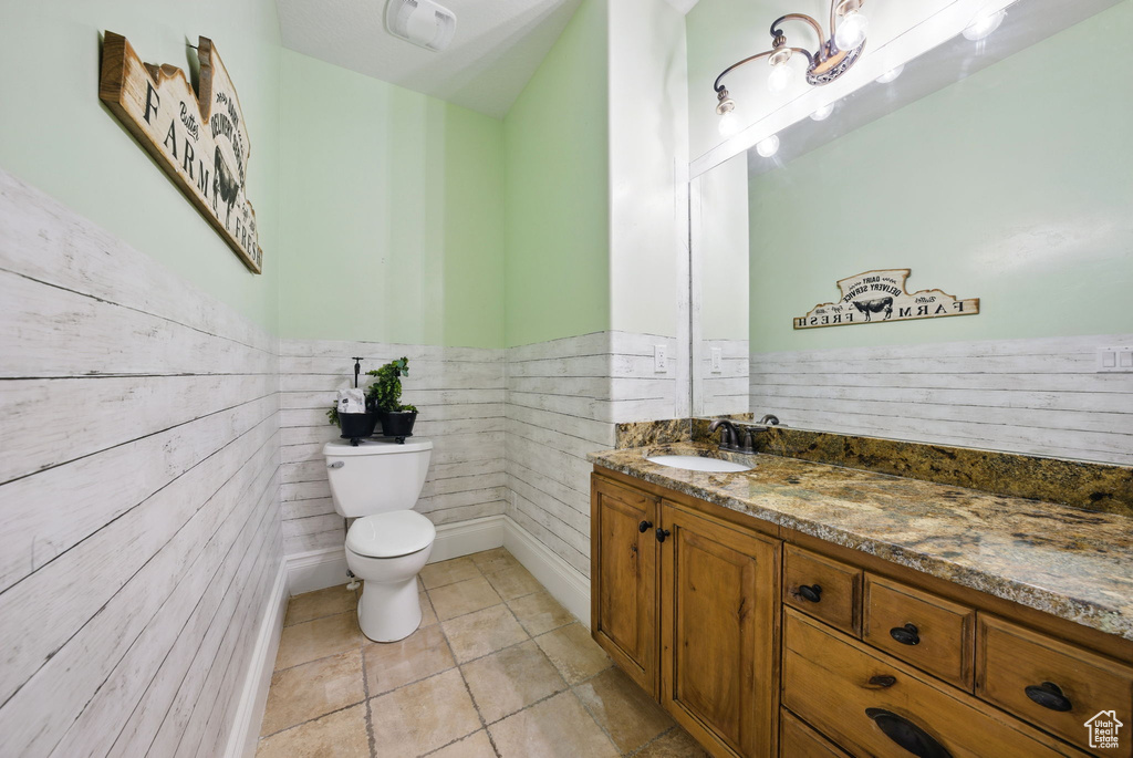 Bathroom with toilet, vanity, wainscoting, and tile patterned floors