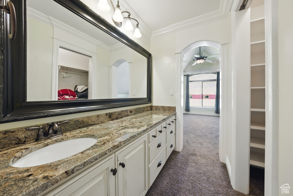 Full bathroom with a spacious closet, vanity, a ceiling fan, and crown molding