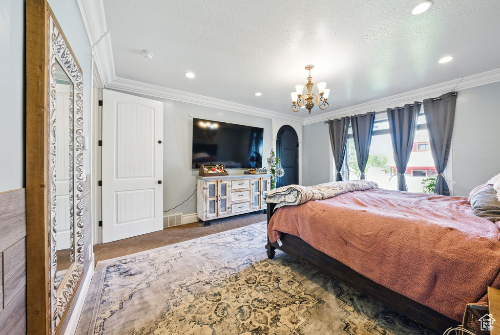 Bedroom with crown molding, a chandelier, carpet, arched walkways, and baseboards