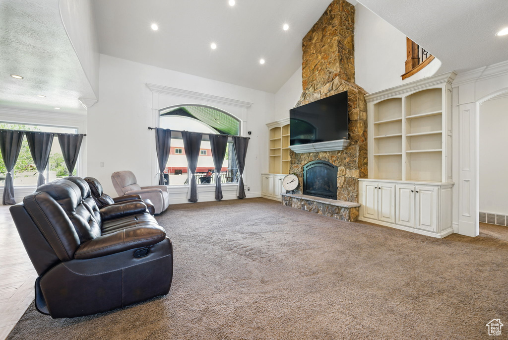Living area featuring high vaulted ceiling, carpet floors, recessed lighting, a fireplace, and built in shelves