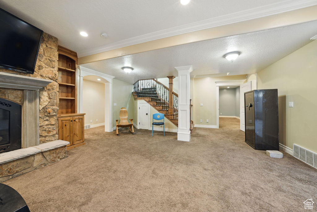Living room with carpet flooring, baseboards, crown molding, stairway, and decorative columns