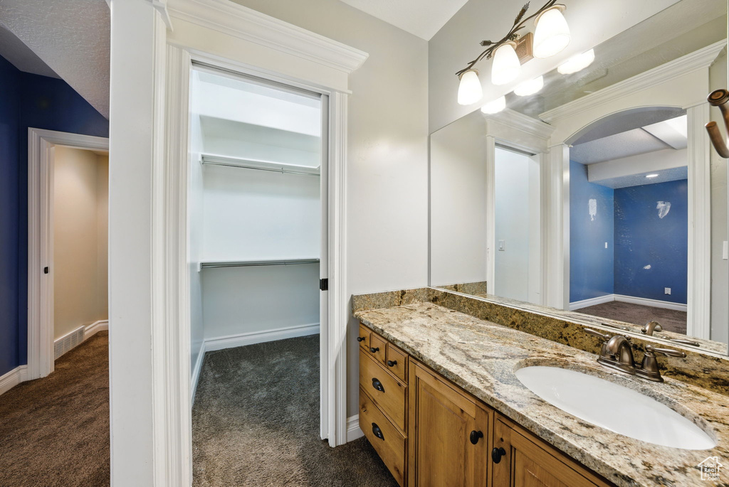 Bathroom with vanity, a walk in closet, and baseboards