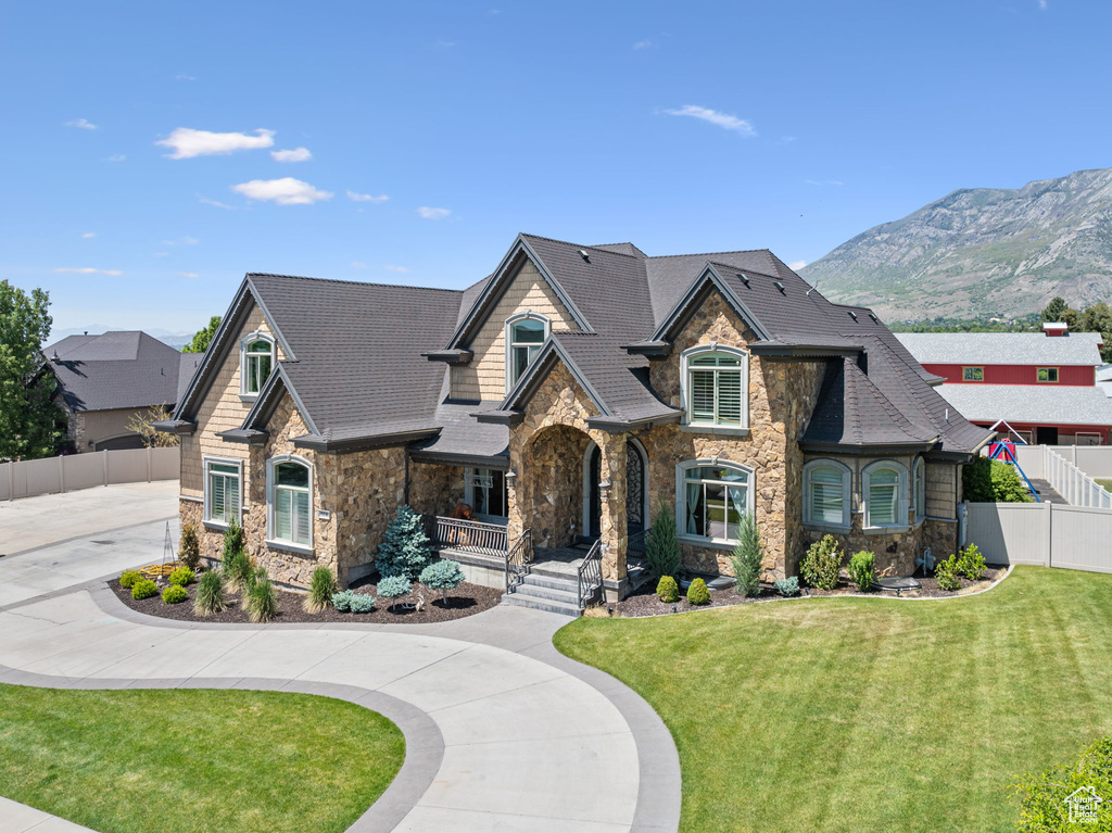 View of front of house with stone siding, a porch, a mountain view, and curved driveway