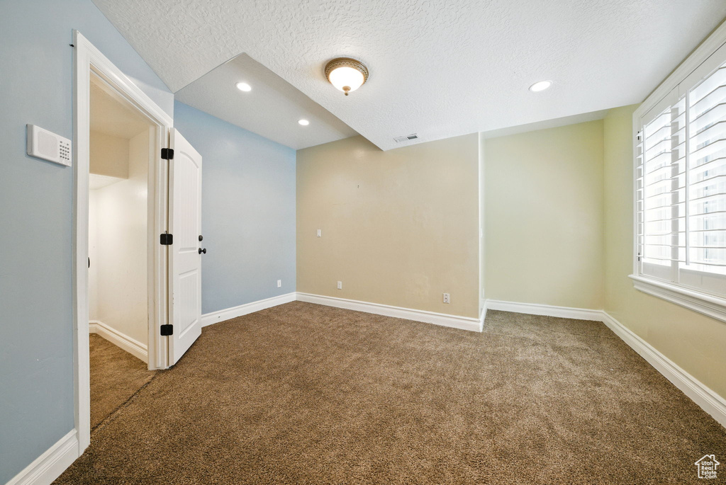 Empty room featuring a textured ceiling, carpet flooring, recessed lighting, and baseboards