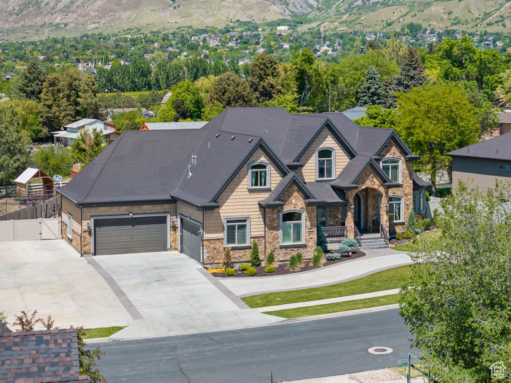 View of front of property featuring stone siding, driveway, a mountain view, a gate, and covered porch