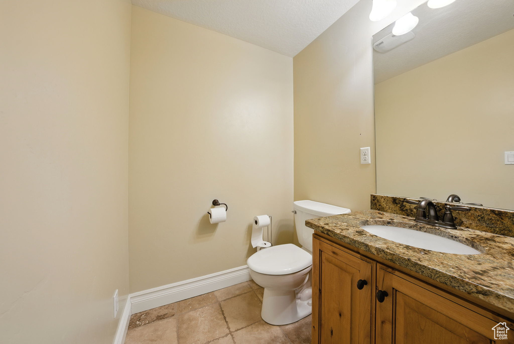 Bathroom featuring toilet, baseboards, and vanity