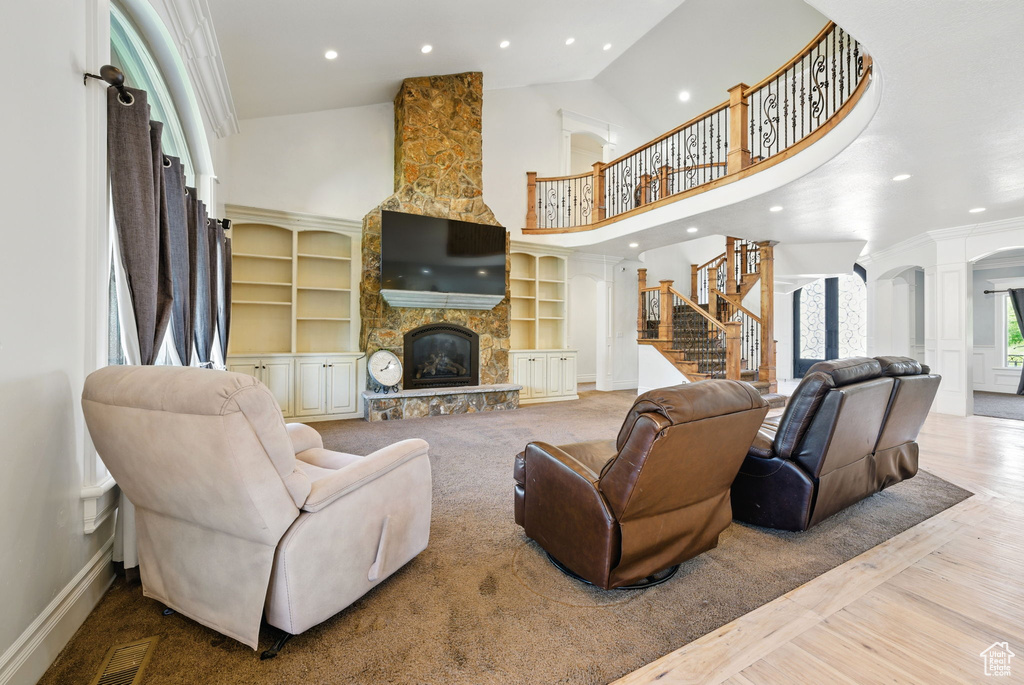 Living area with a towering ceiling, a stone fireplace, recessed lighting, baseboards, and stairway