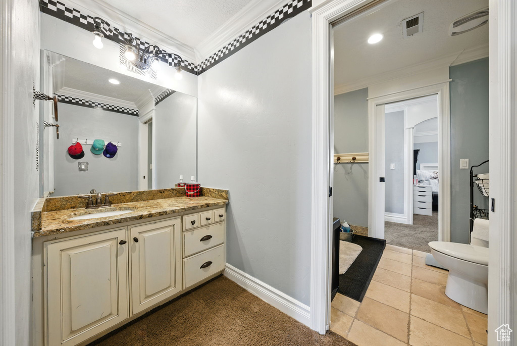 Bathroom featuring ornamental molding, vanity, baseboards, toilet, and tile patterned flooring