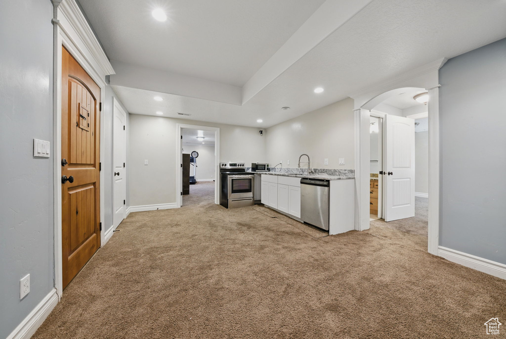 Kitchen with appliances with stainless steel finishes, light colored carpet, recessed lighting, a sink, and light countertops
