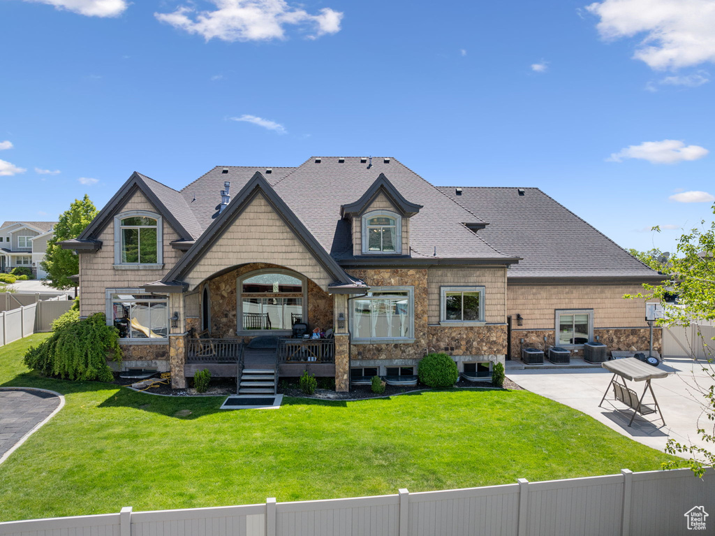 Back of property featuring a patio, a shingled roof, and stone siding