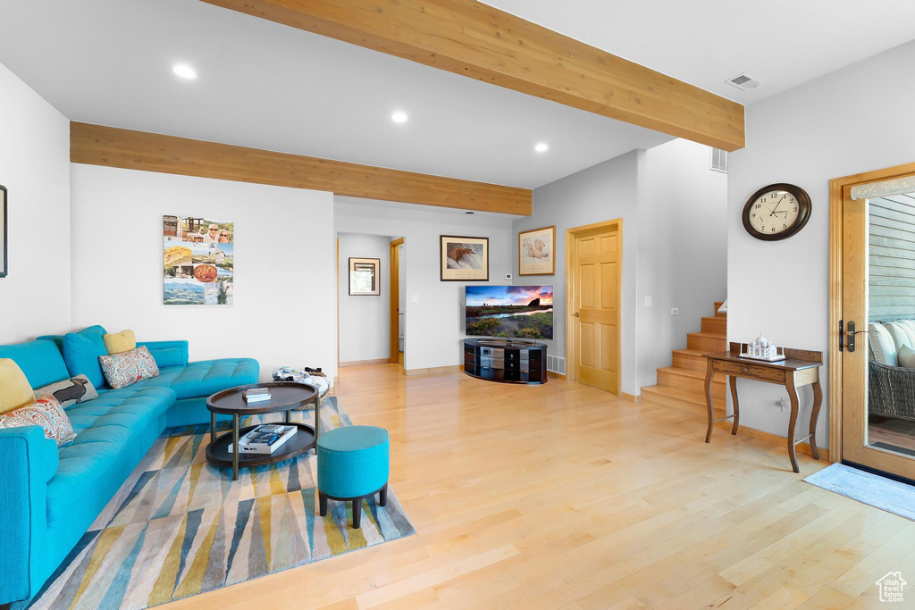 Living room featuring beamed ceiling, light wood-style flooring, stairway, and recessed lighting